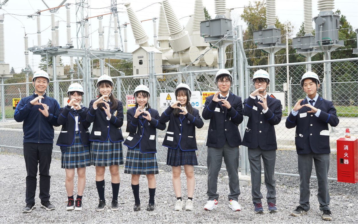 画像：屋外 発電設備の前に集まる生徒たち